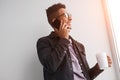 Smiling black man talking on phone and drinking coffee Royalty Free Stock Photo