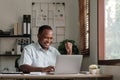 Smiling black man using laptop at home in living room. Happy mature businessman send email and working at home. African Royalty Free Stock Photo