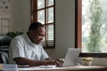 Smiling black man using laptop at home in living room. Happy mature businessman send email and working at home. African Royalty Free Stock Photo