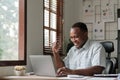 Smiling black man using laptop at home in living room. Happy mature businessman send email and working at home. African Royalty Free Stock Photo