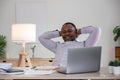 Smiling black man using laptop at home in living room. Happy mature businessman send email and working at home. African Royalty Free Stock Photo