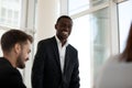 Smiling black mentor stand talking with employees during meeting Royalty Free Stock Photo