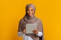 Smiling Black Muslim Girl Using Digital Tablet Standing Over Yellow Background Royalty Free Stock Photo