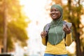 Smiling black muslim woman in headscarf walking by street and listening music on smartphone Royalty Free Stock Photo