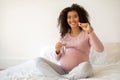 Smiling black pregnant woman showing vitamin pill and holding glass of water Royalty Free Stock Photo