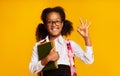 Black Schoolgirl Gesturing Okay Holding School Books On Yellow Background Royalty Free Stock Photo