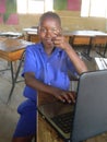 Smiling black schoolkid using laptop showing pointed finnger