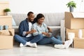 Smiling Black Sposes Sitting With Laptop Among Cardboard Boxes In New House Royalty Free Stock Photo