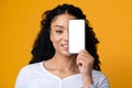 Smiling Black Woman Covering Face With Smartphone With Blank White Screen