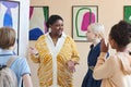 Smiling black woman with group of teenagers in art gallery