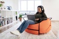 Smiling black woman in headset using laptop at home