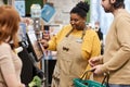 Smiling black woman helping customers with self checkout in supermarket