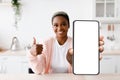 Smiling Black Woman Holding Blank Smartphone In Kitchen And Showing Thumb Up Royalty Free Stock Photo