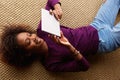 Smiling black woman lying down with digital tablet Royalty Free Stock Photo