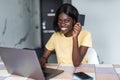 Smiling african woman online shopping using computer and credit card in kitchen Royalty Free Stock Photo