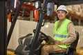 Smiling black woman operating forklift truck in warehouse Royalty Free Stock Photo
