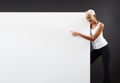 Smiling black woman pointing at a white blank advertising banner sign with copy space. A store and mall advertising billboard for Royalty Free Stock Photo