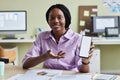 Smiling black woman presenting smartphone with white screen mockup in office Royalty Free Stock Photo