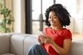 Smiling Black Woman Reading Message On Smartphone, Sitting On Couch At Home Royalty Free Stock Photo