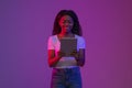 Smiling Black Woman Using Digital Tablet While Standing In Neon Light Royalty Free Stock Photo