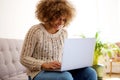 Smiling black woman using laptop computer at home