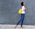 Smiling black woman walking on street with cell phone