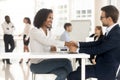 Smiling black woman handshaking with businessman for success conversation. Royalty Free Stock Photo