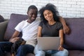 Happy black couple using laptop relaxing with pet at home