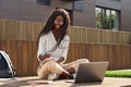 Happy pretty African girl student studying online using laptop sitting outside. Royalty Free Stock Photo