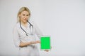 Smiling blond doctor with stethoscope shows the digital tablet. Royalty Free Stock Photo