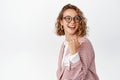 Smiling blond female entrepreneur, office manager in glasses and suit, pointing and looking right, behind her shoulder Royalty Free Stock Photo