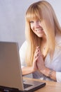 Smiling blond girl chatting online with computer