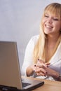 Smiling blond girl chatting online with computer