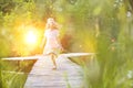 Smiling blond girl running on pier at lakeshore with yellow lens flare in background Royalty Free Stock Photo