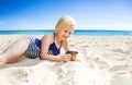 Smiling blond girl on seashore viewing photos on camera Royalty Free Stock Photo