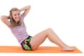 Smiling blond woman training stomach muscles on a mat.