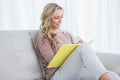 Smiling blonde on couch taking notes on notebook Royalty Free Stock Photo