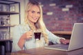 Smiling blonde drinking coffee and using laptop Royalty Free Stock Photo