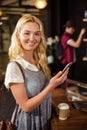 Smiling blonde drinking coffee and using smartphone Royalty Free Stock Photo