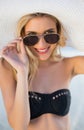 Smiling blonde in elegant black bikini looking over her sunglasses Royalty Free Stock Photo