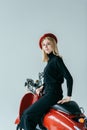 Smiling blonde girl in black clothes posing by red motorcycle Royalty Free Stock Photo