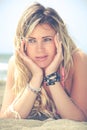 Smiling blonde happy girl at sea lying on the beach. Two hands under her face