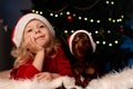 smiling blonde little girl in Christmas dress and Santa hat with toy Terrier dog Royalty Free Stock Photo