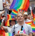Smiling blonde man, lots of rainbow Pride flags in the background