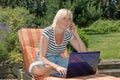 Smiling blonde middle aged woman is calling outdoors