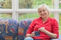 Smiling blonde middle-aged woman is relaxing on a sofa Royalty Free Stock Photo