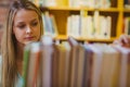 Smiling blonde picking out a book of bookshelves Royalty Free Stock Photo