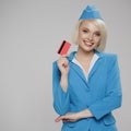 Smiling blonde stewardess holding credit card in her hand.