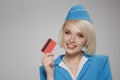 Smiling blonde stewardess holding credit card in her hand.