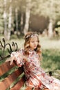 Smiling blonde teen girl posing in summer garden. Wearing flower wreath outdoors Royalty Free Stock Photo